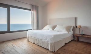 a bedroom with a large bed and a large window at BYPILLOW Cap Sa Sal in Begur