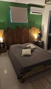 - une chambre avec un grand lit et un mur vert dans l'établissement Villa k'nel, à Rivière-Pilote