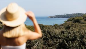 イエールにあるLe Domaine de la mer - Beach hotel Nature&Authenticité Hyèresの帽子をかぶって海を眺める人
