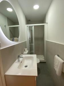 Baño blanco con lavabo y espejo en Gran Vía Urban Apartments, en Madrid