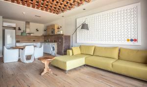 a living room with a yellow couch and a kitchen at BYPILLOW Cap Sa Sal in Begur