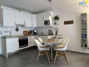 a kitchen with white cabinets and a table and chairs at Villa Vivaldi Ferienwohnung 2 in Wangerooge