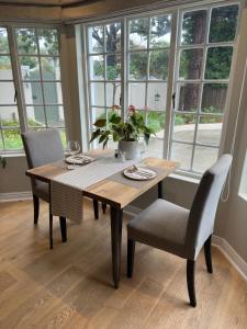 Camellia Cottage - Bay Room في كيب تاون: طاولة طعام وكراسي مع طاولة ونوافذ