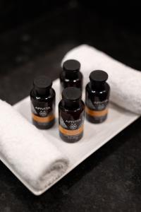 three bottles of essential oils on a plate with towels at Nevma Suites in Firostefani