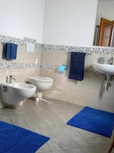 ein Badezimmer mit einem WC, einem Waschbecken und blauen Matten in der Unterkunft B&B Tequila in Olbia