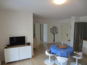 ein Wohnzimmer mit Tisch und Stühlen und einem Fernseher in der Unterkunft Rez de Jardin T3 recent et calme au Nouvelles Terres à La Londe les Maures in La Londe-les-Maures