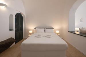 a bedroom with a white bed with two lamps and mirrors at Nevma Suites in Firostefani