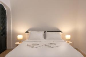 a white bed with two white towels on it at Nevma Suites in Firostefani