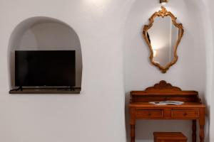 a room with a tv and a mirror and a table at Nevma Suites in Firostefani