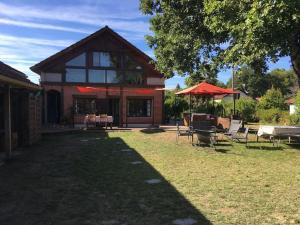 a house with chairs and umbrellas in the yard at Appartement chez Loulou in Léon