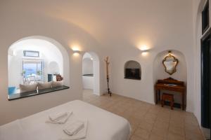 a bedroom with a bed and a table and a mirror at Nevma Suites in Firostefani