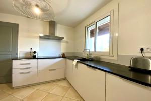 eine Küche mit weißen Schränken, einem Waschbecken und einem Fenster in der Unterkunft La Castelnauvienne- 3 bedroom villa with swimming pool! in Castelnau-le-Lez