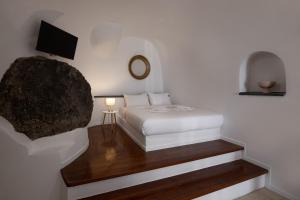 a bedroom with a white bed and a tv at Nevma Suites in Firostefani