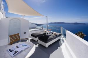 a balcony with a couch and chairs on the water at Nevma Suites in Firostefani