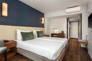 a bedroom with a large white bed and a desk at Hotel Baia in Cascais