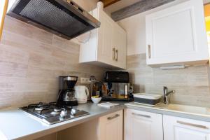 uma cozinha com armários brancos e um forno com placa de fogão em La maisonnette du Vivier em Couffy