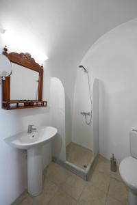 a bathroom with a sink and a mirror and a toilet at Nevma Suites in Firostefani