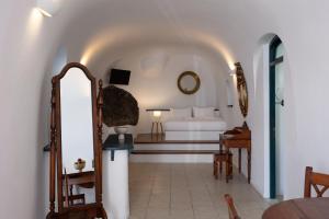 a bedroom with a bed and a table and a mirror at Nevma Suites in Firostefani