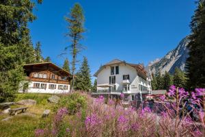 ein Haus in den Bergen mit einem Blumenfeld in der Unterkunft Hotel und Naturresort Handeck in Guttannen