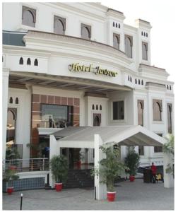 - un grand bâtiment blanc avec un parasol devant dans l'établissement Hotel Javson, à Sialkot