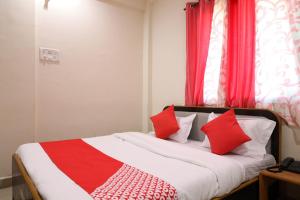 a bedroom with a bed with red and white pillows at OYO Prithvi Inn in Dhantoli
