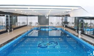 a large swimming pool with blue water in a building at Hotel Javson in Sialkot