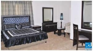 1 dormitorio con cama, espejo y silla en Hotel Javson, en Sialkot