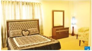 a bedroom with a bed and a dresser and a mirror at Hotel Javson in Sialkot