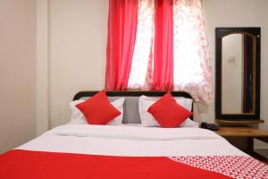 a bedroom with a bed with red pillows and a mirror at OYO Prithvi Inn in Dhantoli