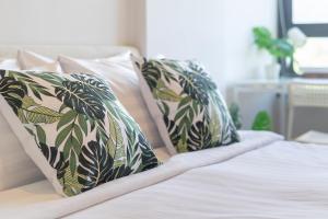 a bed with green and white pillows on it at ZcapeX2 Condo near Boat Avenue & Laguna in Bang Tao Beach