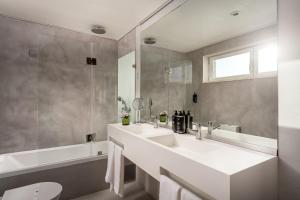 a white bathroom with a sink and a tub at Hotel Baia in Cascais