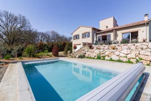 uma piscina em frente a uma casa com uma parede de pedra em La Tendresse - Maison Familliale avec Piscine em Mondonville