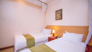 ein Hotelzimmer mit 2 Betten mit weißer Bettwäsche in der Unterkunft Longview Luxury Resort in Nairobi