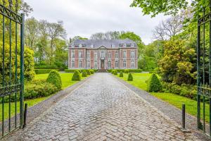 an open gate to a large house with a brick driveway at Château des Ablens in Leuze-en-Hainaut
