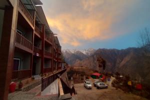two cars parked in a parking lot with mountains in the background at Satine Resort Auli in Joshīmath