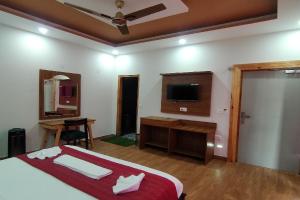 a bedroom with a bed and a desk and a television at Satine Resort Auli in Joshīmath