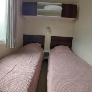 2 letti in una piccola camera da letto con finestra di Mobilhome 6 pers PLAGE À 500M a Plage dʼArgelès