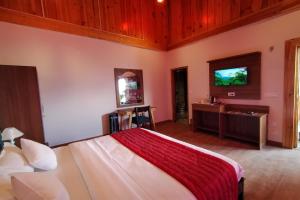 a bedroom with a bed and a flat screen tv at Satine Resort Auli in Joshīmath