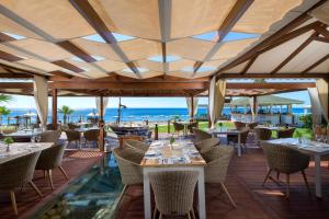 un restaurant avec des tables et des chaises et l'océan en arrière-plan dans l'établissement Rodos Palladium Leisure & Wellness, à Faliraki