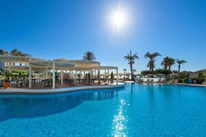 une grande piscine bleue avec des tables et des chaises dans l'établissement Rodos Palladium Leisure & Wellness, à Faliraki