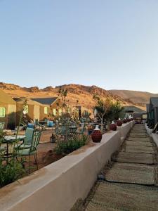 a retaining wall with chairs and tables in a yard at The Friendly Camp in Zagora