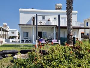 a white house with two chairs in a yard at Ammos Beachfront Villa Paradise in Larnaca