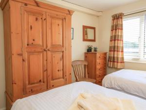 Un dormitorio con un gran armario de madera y una cama. en 3 The Salcombe, en Salcombe 12 fotos más