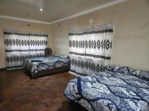 een slaapkamer met 2 bedden en gordijnen aan de muur bij Stay Sunrise in Nelspruit