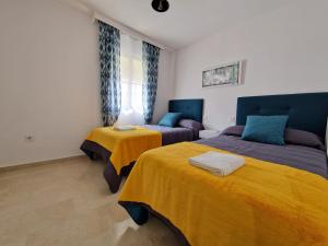 two beds in a room with yellow and blue at DICHA 24 in Seville