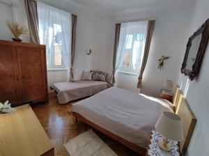 a bedroom with two beds and a table and two windows at APARTMAN RIVA 2 in Komiža