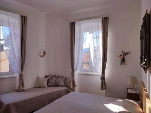 a bedroom with two beds and two windows at APARTMAN RIVA 2 in Komiža