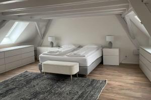 a white bedroom with a bed and a chair at Amazing two bedroom Penthouse in the city centre (Canal1) in Zurich