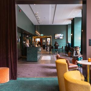 a lobby of a hotel with people sitting at tables at Hotell Bondeheimen in Oslo