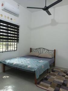 Bett in einem Zimmer mit Deckenventilator in der Unterkunft Homestay Lembah Tambunan in Kampong Nail